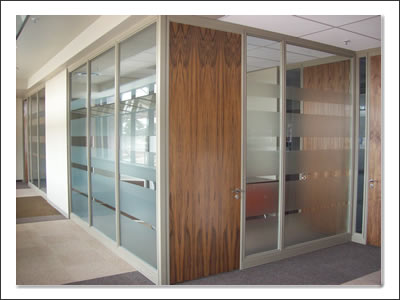 A Cliplok 54 office space incorporating glass partitioning with wooden panel doors, balancing transparency and warmth in a professional setting.