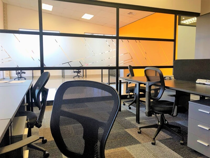 A Cliplok 54 office partition with black metal framing and frosted glass panels, separating workstations while maintaining an open feel.